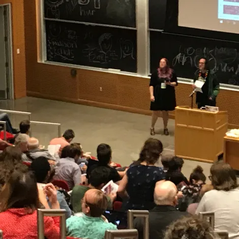 Two people address crowd of people in an auditorium